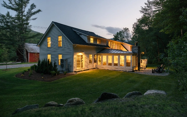 Wide view of the Mile Away farmhouse at dusk surrounded by trees